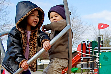 Two young children climb on a new playground