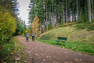 Two cyclists ride down the unpaved Green to Cedar River Trail