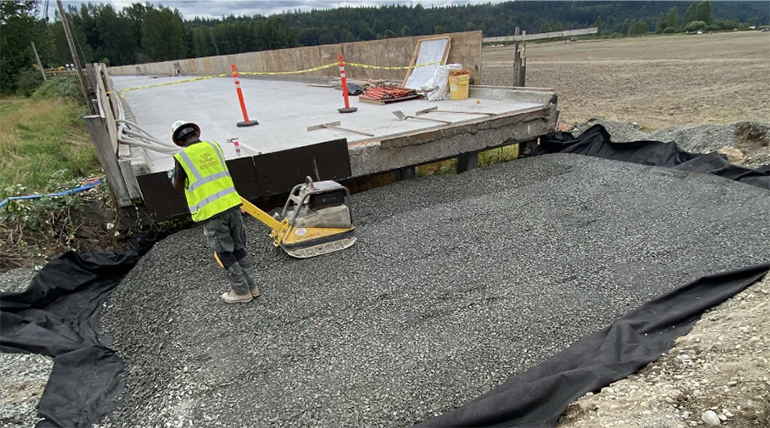 Gravel material being applied to support new bridge approach.